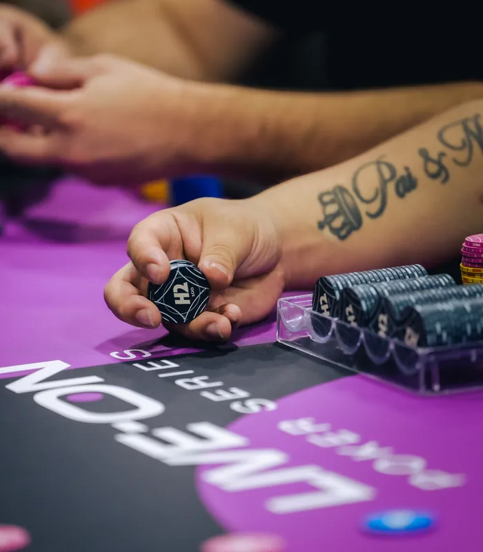 Jogador segurando fichas de poker na mesa do H2