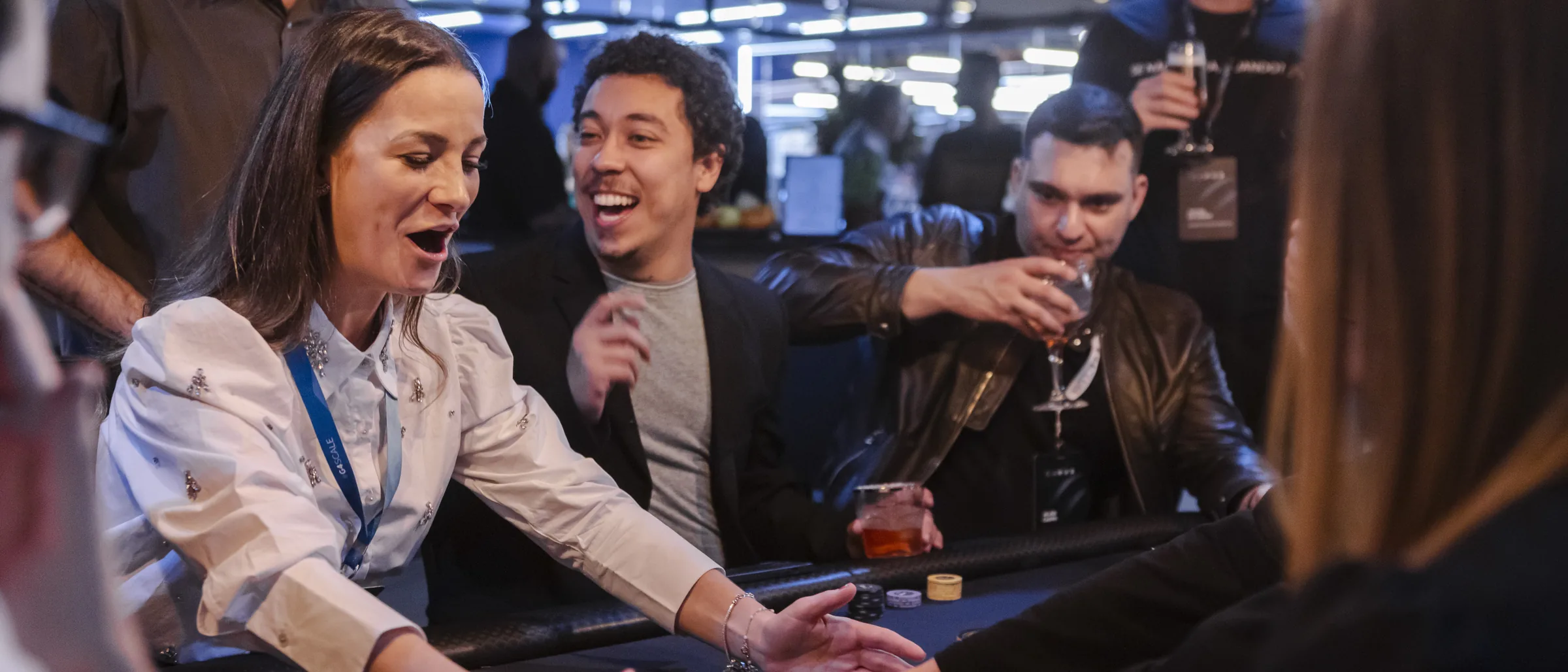 Grupo de amigos rindo e brindando na mesa de poker do H2