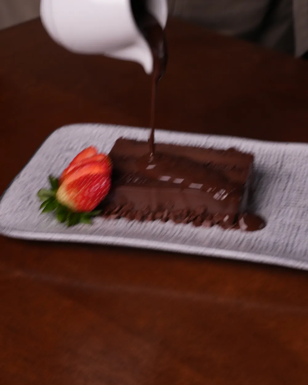 Calda de chocolate sendo servida sobre o bolo