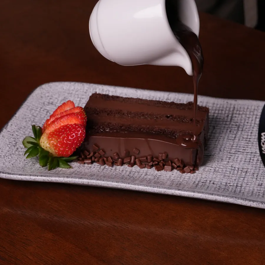 Bolo de chocolate recebendo calda de ganache quente