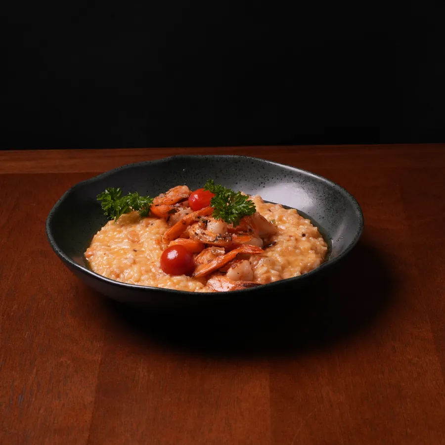 Risoto cremoso de camarão finalizado com tomate e salsinha